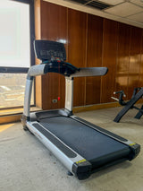 Lifefitness treadmill with a digital display console is shown in an indoor gym setting with other exercise equipment in the background.
